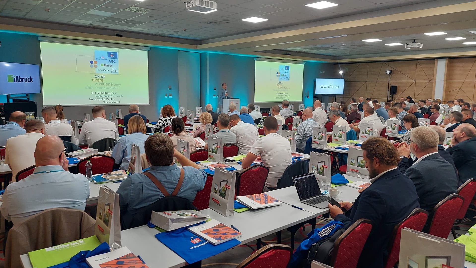 Účastníci odbornej konferencie SLOVENERGOokno 2025 v konferenčnej sále, prednáška na dvoch projekčných plátnach.
