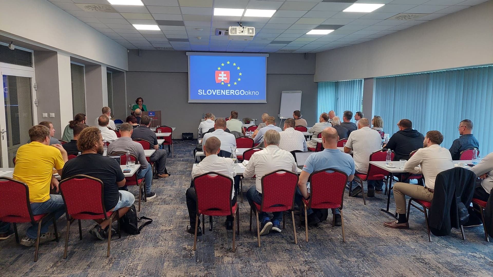 Účastníci výročnej členskej schôdze SLOVENERGOokno v zasadacej sále, logo združenia na projekčnom plátne.